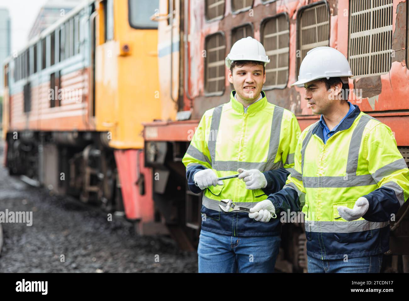 Lokomotivreparaturarbeiter Happy Relax Talk mit Freunden Team nach dem Ende der Arbeit alten Zug auf der Eisenbahnstrecke draußen im Lokomotivdepot. Stockfoto