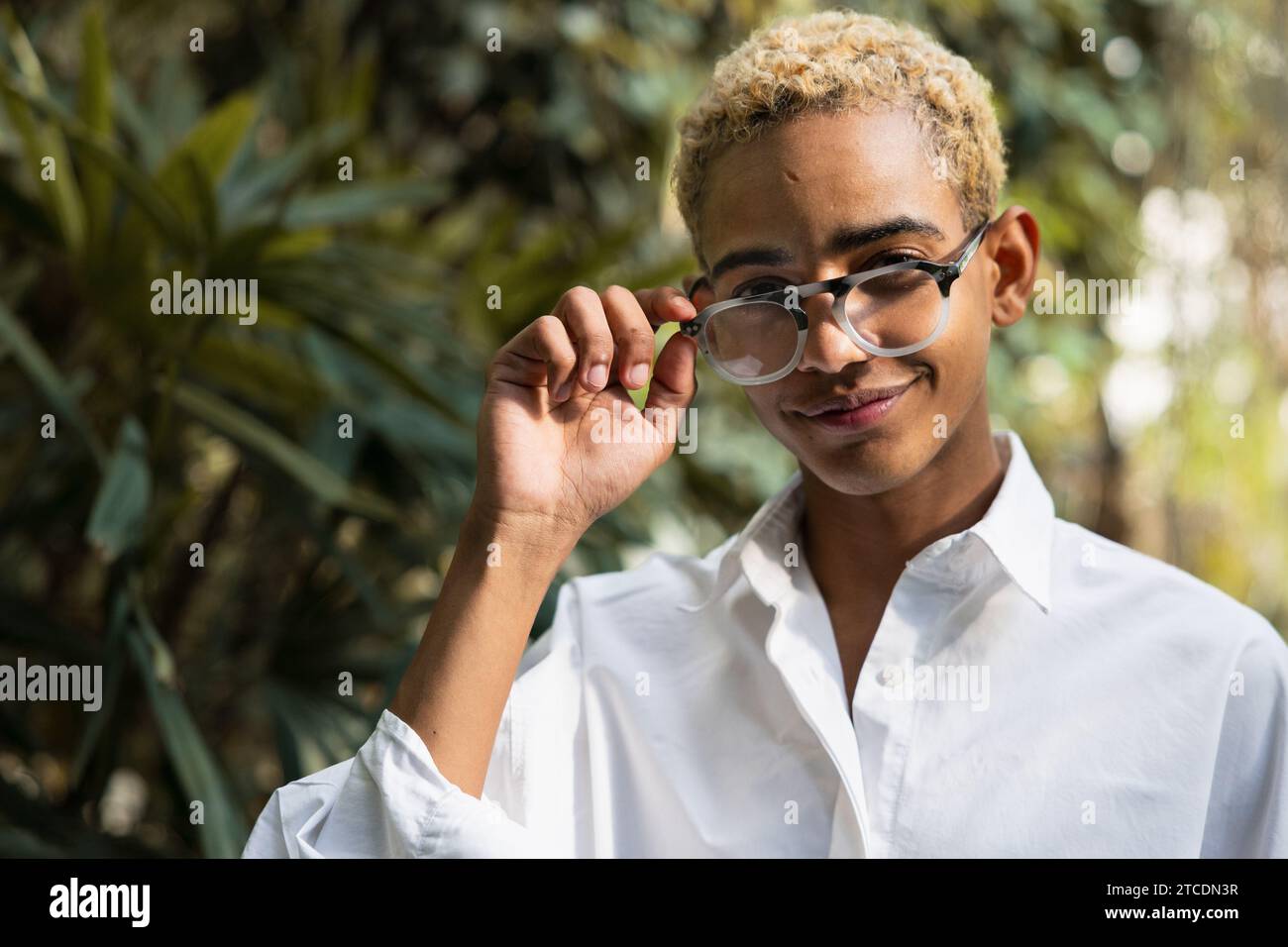 Porträt eines jungen schwarzen Mannes mit blondem Haar mit Sehgläsern im Gewächshaus Stockfoto