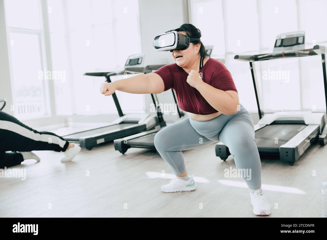 Frauen in Übergröße, die VR-Headset verwenden, genießen visuelle Sport-Fitness-Spielübungen. Menschen, die moderne Technik für das Heilbehandlungskonzept nutzen. Stockfoto