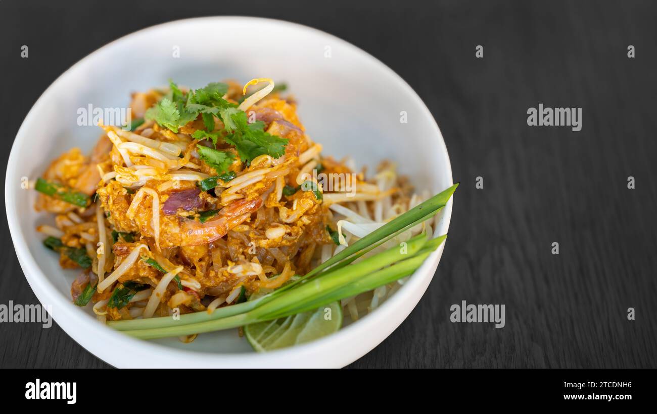 Pad thai Koriander oben saftig cremig lecker köstlich weltweit beliebt. Berühmte thailändische Essenskarte in der Schüssel auf schwarzem Holztisch. Stockfoto