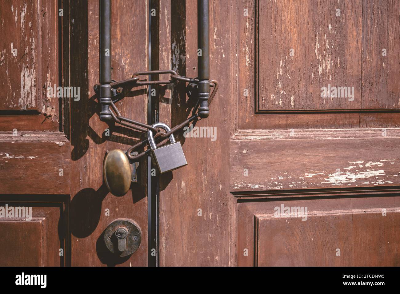 Alte Holztür mit rostigem Kettenschloss verschlossen. Geschlossenes verlassenes Haus, niemand lebt, Leute verlassen und verkaufen ihr Haus. Stockfoto