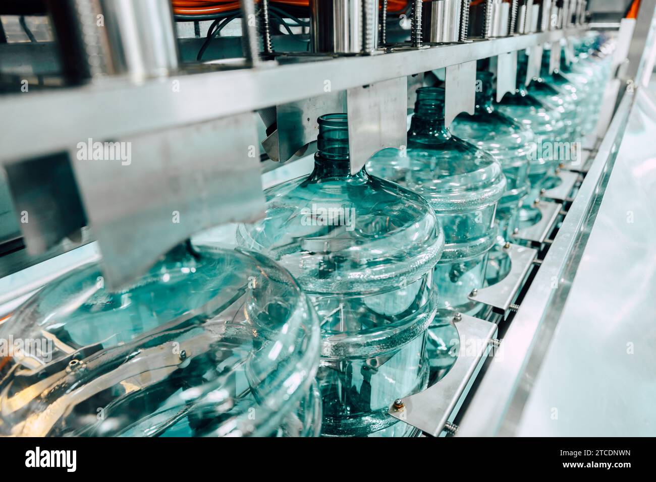 PET-Trinkwasser-Gallonenflasche aus Kunststoff sauber in der Förderband-Produktionslinie in der Trinkwasserfabrik. Stockfoto