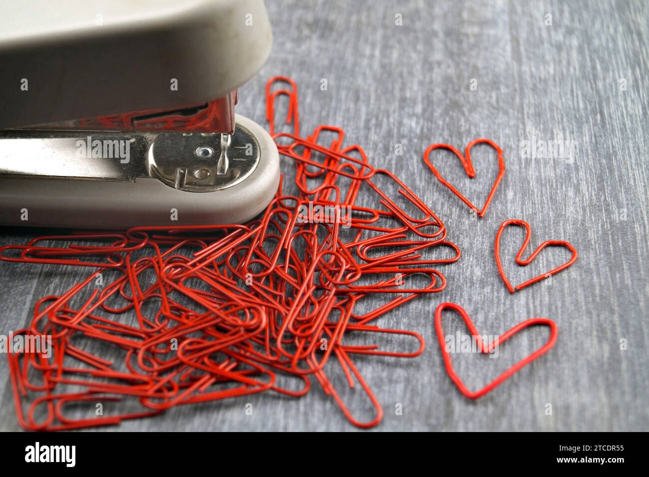 Hefter mit roten Büroklammern, drei davon herzförmig, Liebe im Büro Stockfoto