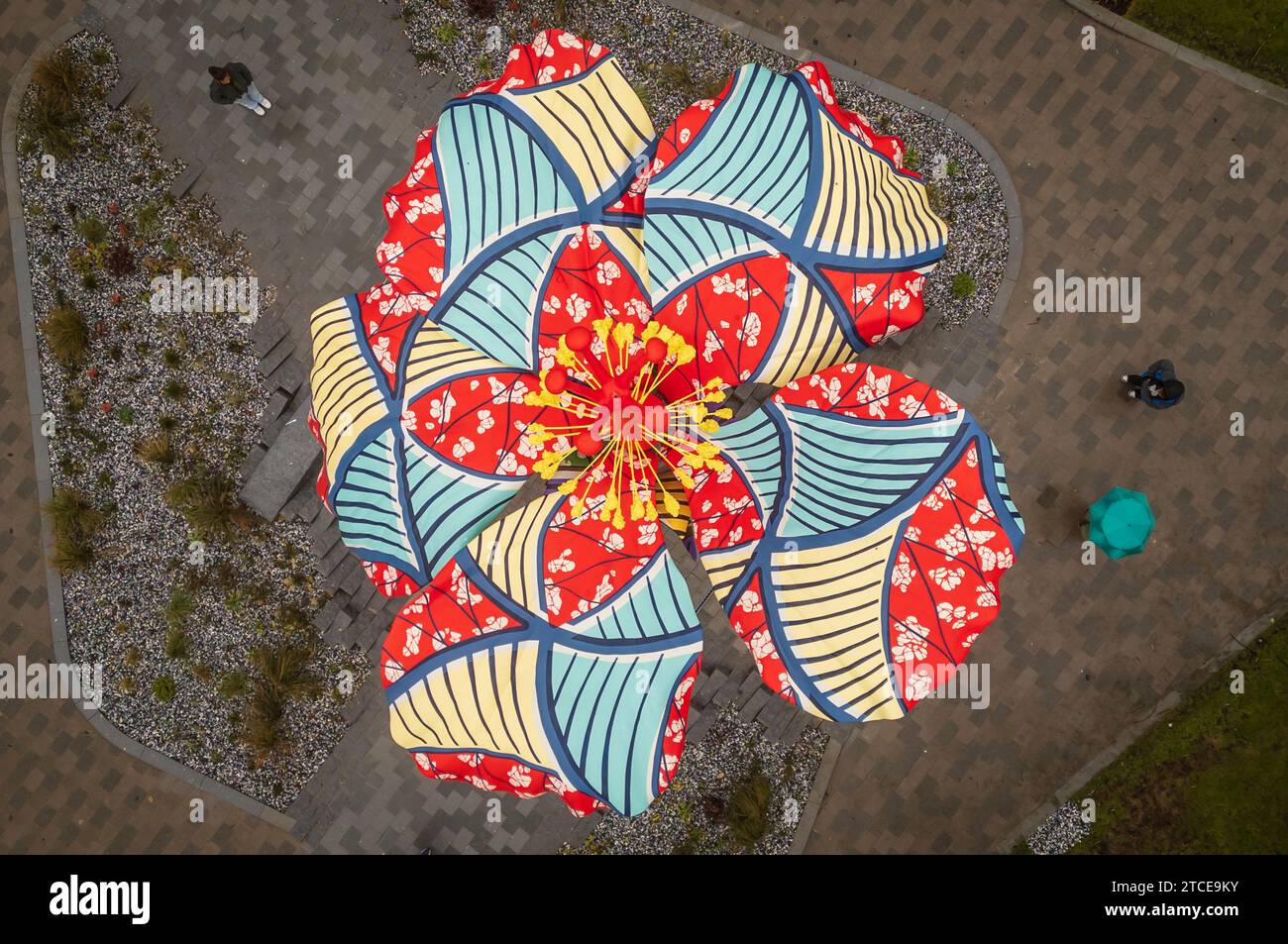 Mitglieder des Leeds 2023 Year of Culture Teams posieren während eines Fotoanrufs und betrachten den Hibiscus Rising, eine 9,5 Meter hohe Skulptur, die von der Hibiskusblume inspiriert wurde und von der internationalen Künstlerin Yinka Shonibare CBE geschaffen wurde. Sie ist im South Bank, nahe dem Fluss Aire in Leeds zu sehen. im Rahmen des Jahres 2023 in Leeds. Das öffentliche Kunstwerk zeigt Shonibares afrikanisch inspirierte Batikmuster, die Themen kultureller und nationaler Identität thematisieren. Die Skulptur ist in der Nähe des Flusses Aire zu sehen, wo ein britischer nigerianischer Bewohner von Leeds, David Oluwale, am 18. April 1969 zu seinem Tod gejagt wurde. Pi Stockfoto