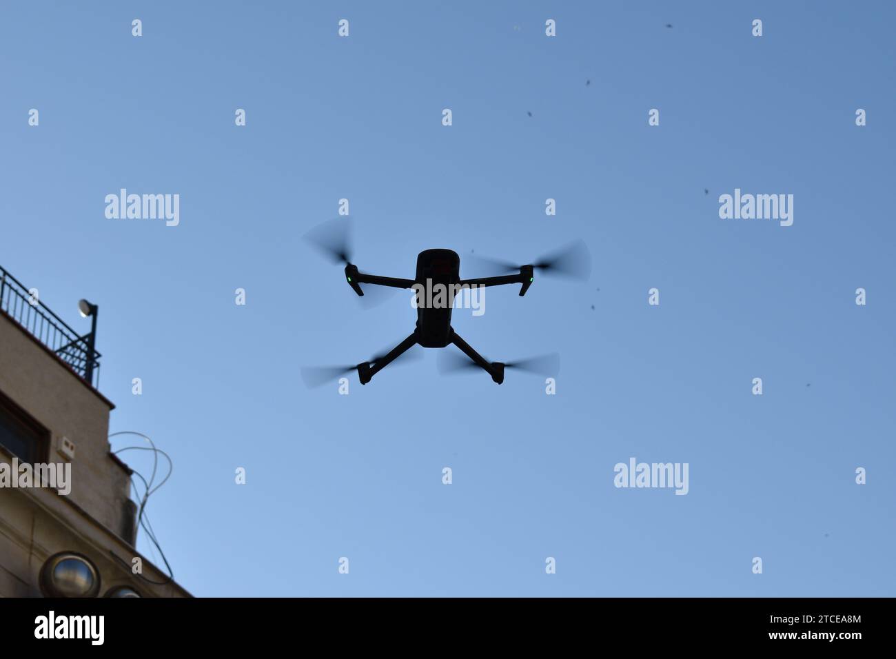 Silhouette einer Drohne, die in der Luft schwebt, mit klarem blauem Himmel als Hintergrund Stockfoto