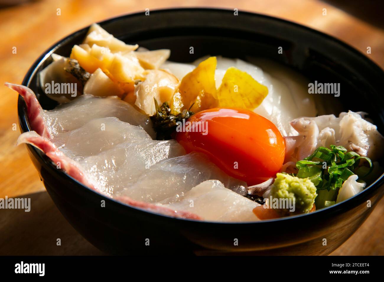 Japanische Sashimi Donburi mit Weißfisch, Tintenfisch und Eigelb auf einem Bett aus weißem Reis. Stockfoto