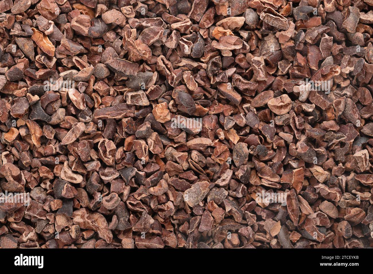 Kakaospitzen. Hintergrund mit zerstoßenen getrockneten, fermentierten Kernen von Kakaobohnen, Samen von Theobroma cacao, im Allgemeinen zu Schokolade verarbeitet. Stockfoto