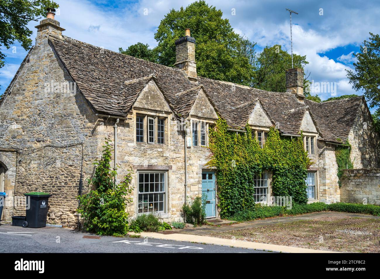 Malerische Reihe von Steinhäusern am Fuße der Burford High Street (A361) neben der Brücke über den Fluss Windrush in Burford, Oxfordshire, England, Großbritannien Stockfoto