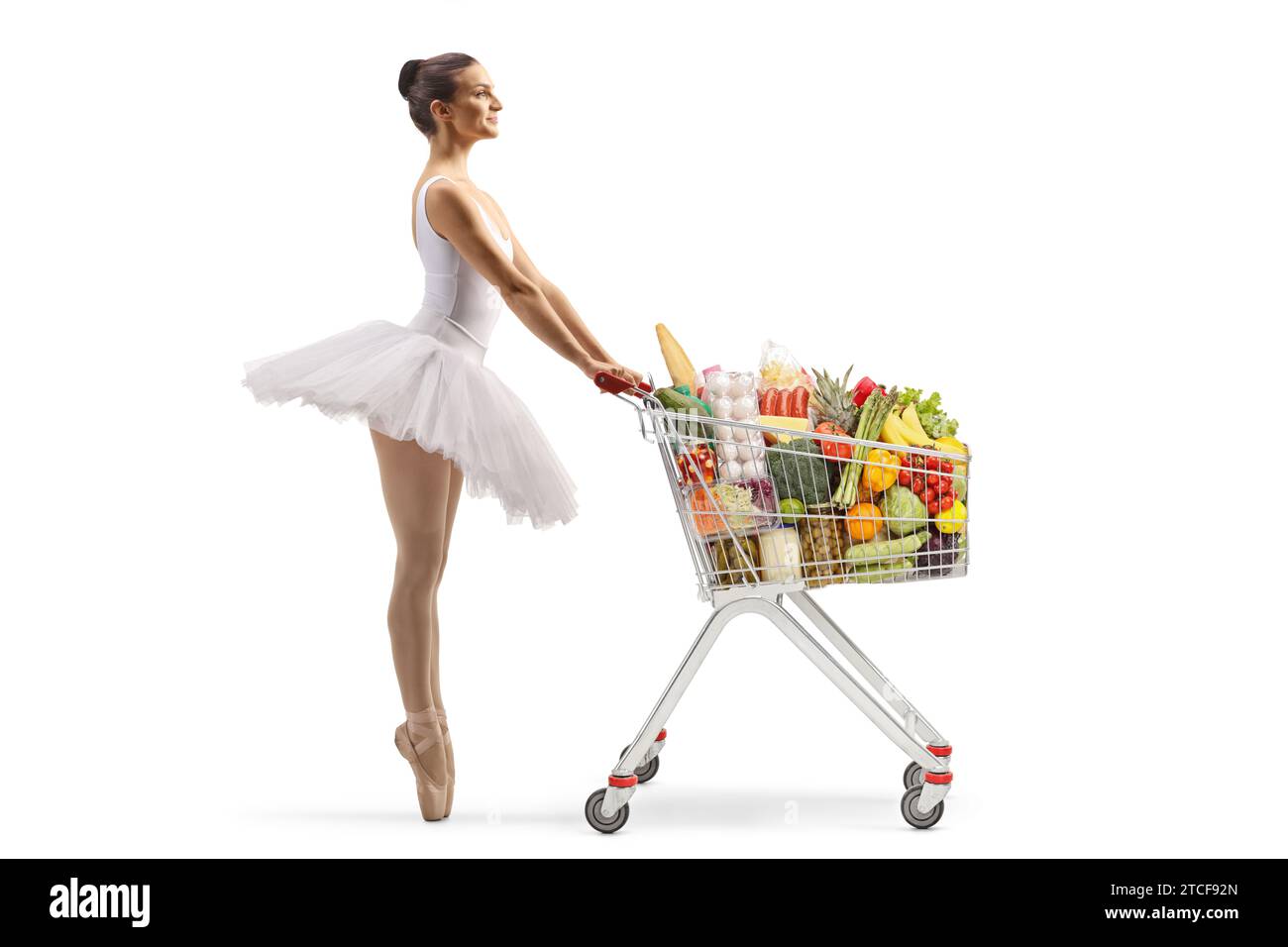 Profilaufnahme einer Ballerina in voller Länge, die mit Essen in einem Einkaufswagen wartet, isoliert auf weißem Hintergrund Stockfoto