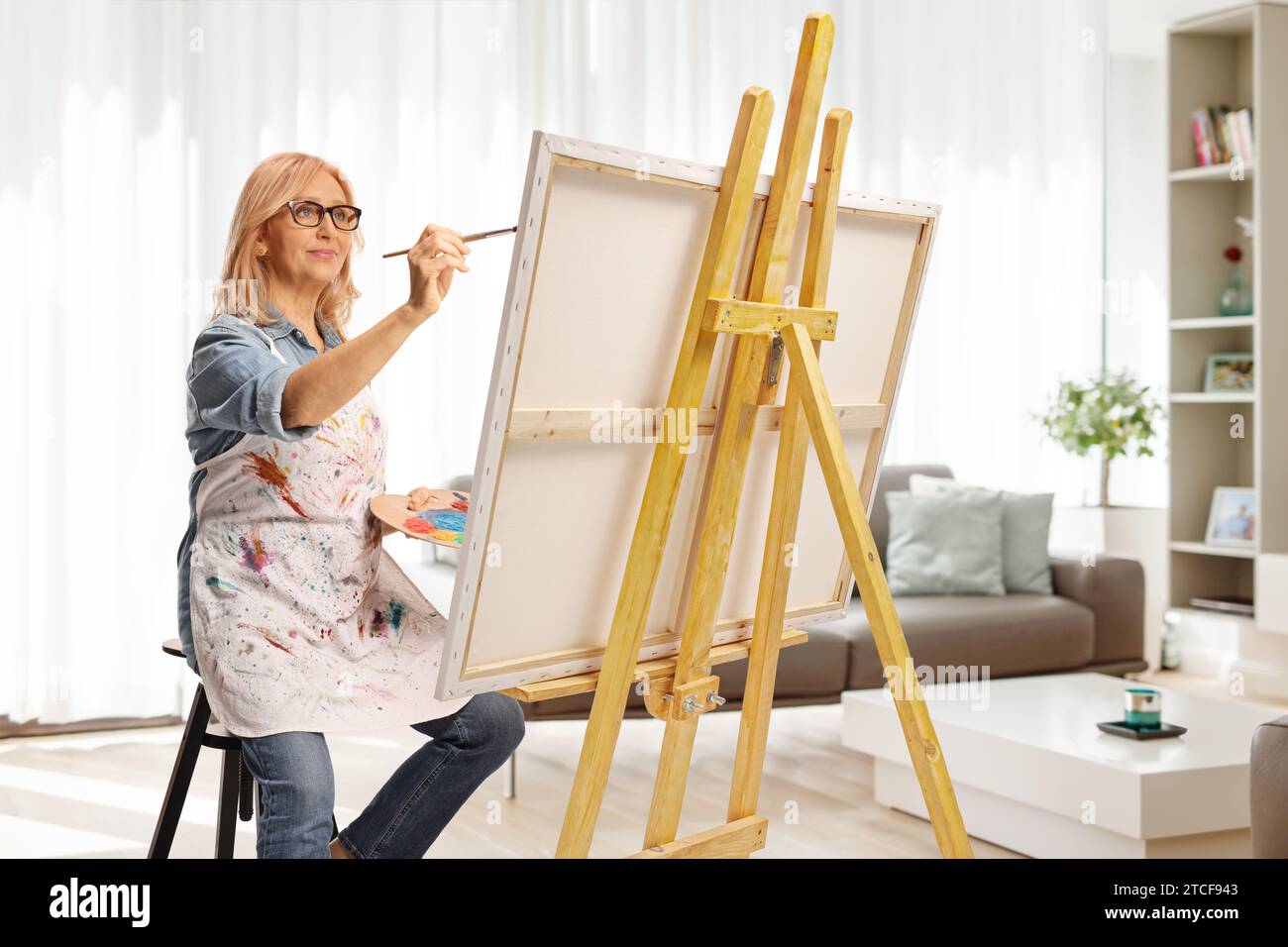 Frau mit Pinsel und Palette mit Acrylfarbe und Malerei zu Hause Stockfoto