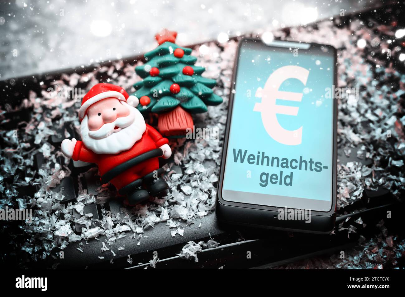 FOTOMONTAGE, Smartphone mit Aufschrift Weihnachtsgeld, Weihnachtsmannfigur und Tannenbaum auf Computertastatur *** FOTOMONTAGE, Smartphone mit Aufschrift Weihnachtsbonus, Weihnachtsmannfigur und Weihnachtsbaum auf Computertastatur Stockfoto