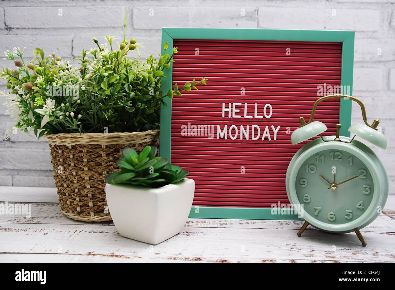 Hallo-Montag-Text auf Brieftafel mit Alarmtafel und künstlicher Pflanzendekoration Stockfoto