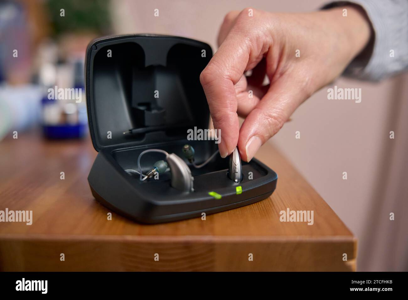 Nahaufnahme Einer Person, Die Zu Hause Ein Drahtloses Hörgerät Oder Gerät Aus Der Ladetasche Abholt Stockfoto