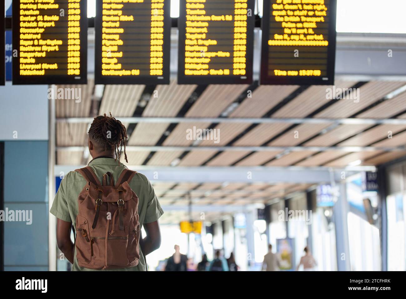 Rückansicht Eines Mannes Mit Rucksack Und Blick Auf Die Tafel Für Die Abfahrt Am Bahnhof Stockfoto