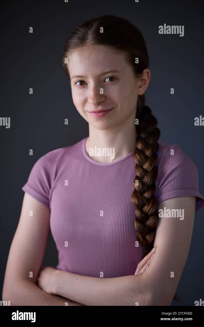 Low Key Studio Porträt Eines Fröhlich Lächelnden Und Selbstbewussten Teenager-Mädchens, Das Die Kamera Ansieht Stockfoto