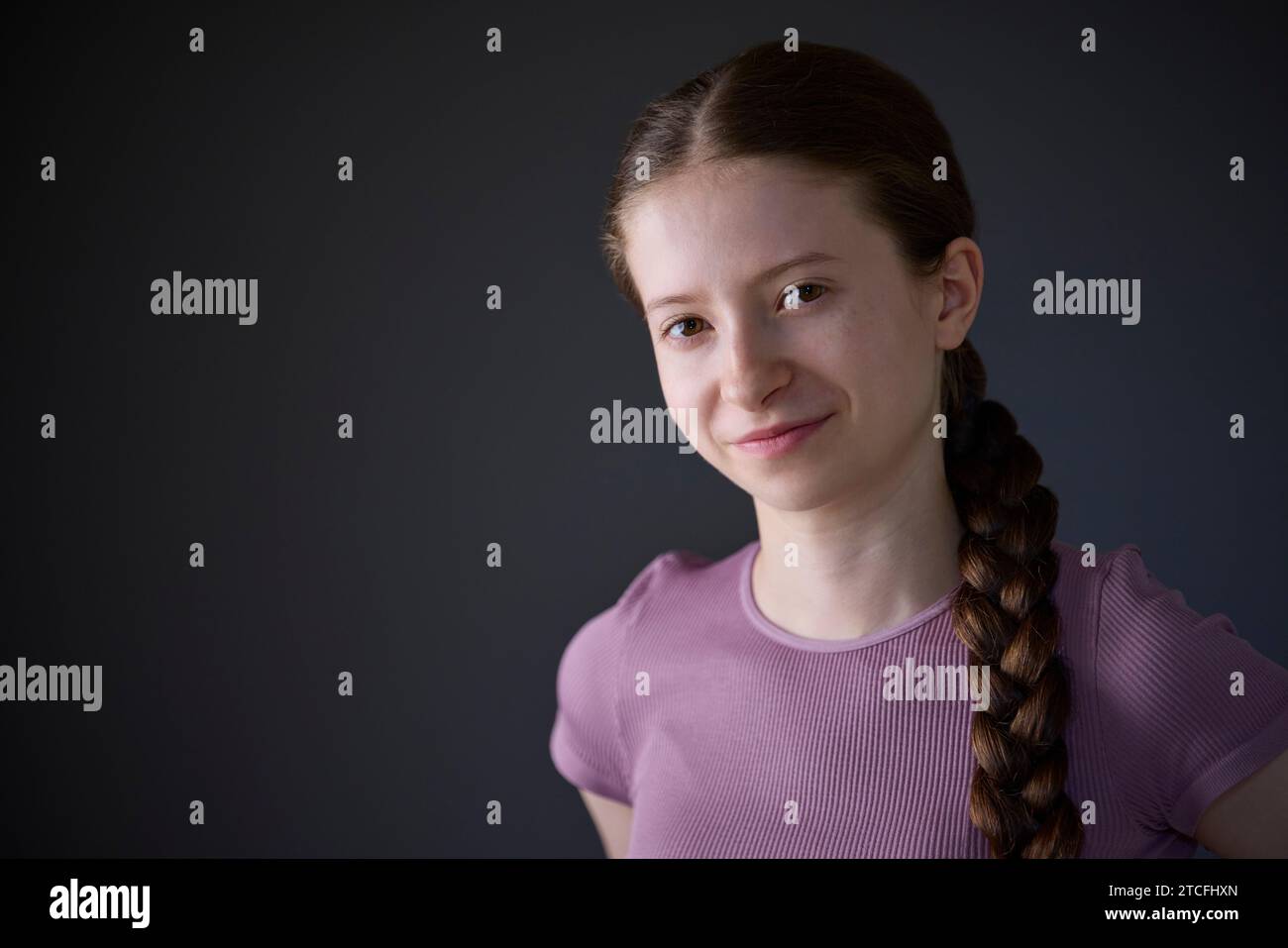 Low Key Studio Porträt Eines Fröhlich Lächelnden Und Selbstbewussten Teenager-Mädchens, Das Die Kamera Ansieht Stockfoto