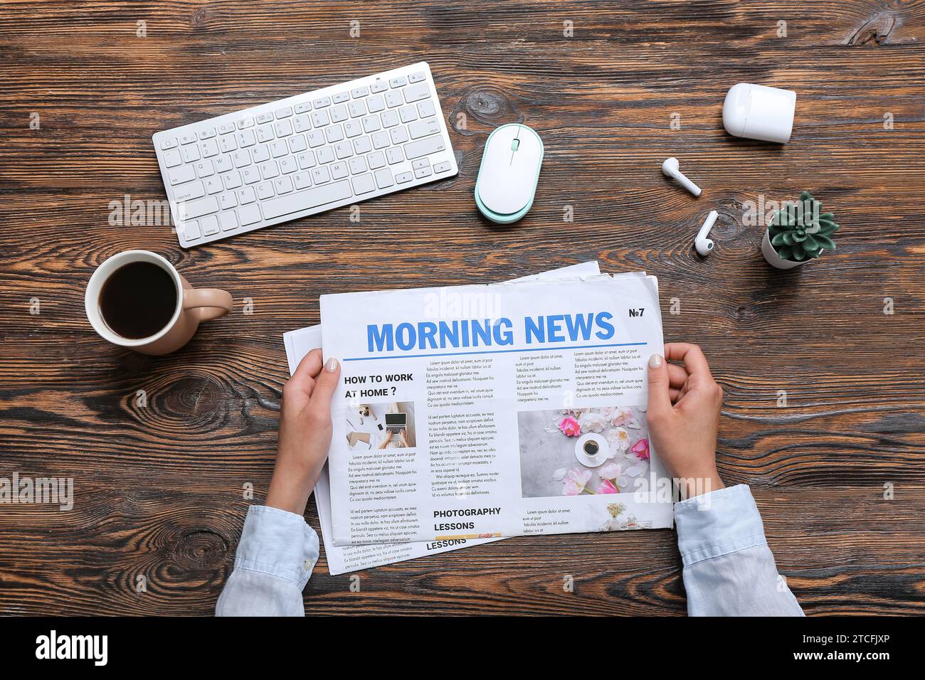 Frau, die am Arbeitsplatz Zeitung liest, mit einer Tasse Kaffee auf Holzhintergrund Stockfoto