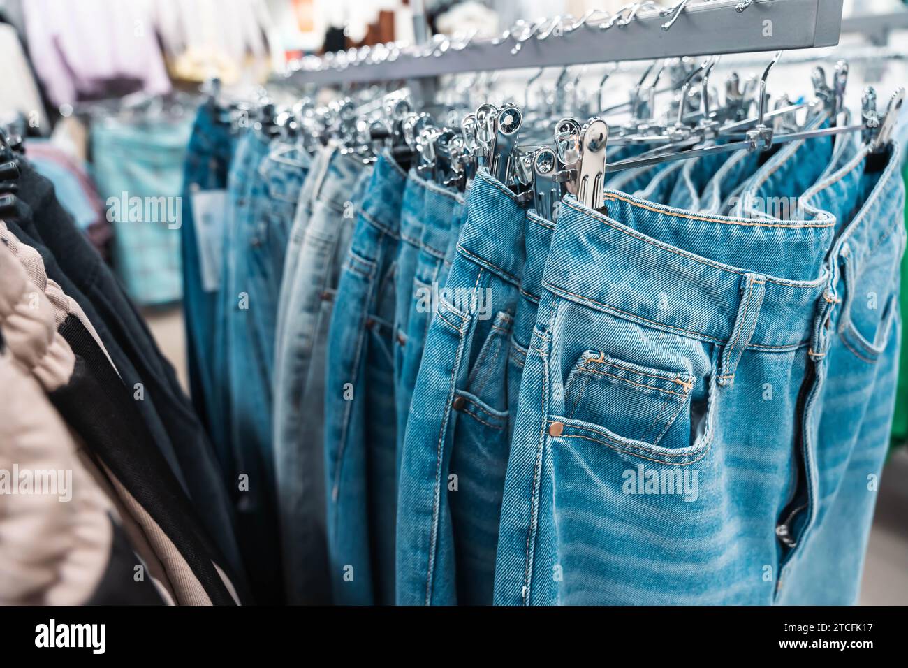 Eine trendige blaue Jeans auf einem eleganten Kleiderbügel, die in einem schicken, modernen Boutique-Ambiente hängt und die neueste Freizeitkleidung repräsentiert Stockfoto