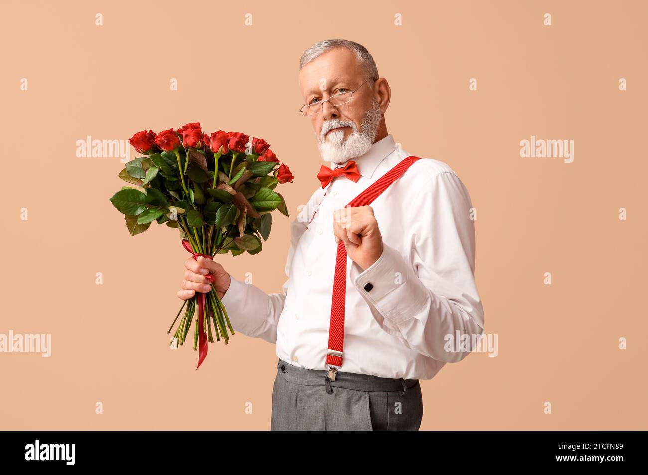 Reifer Mann mit Rosenstrauß auf beigefarbenem Hintergrund. Valentinstag Stockfoto