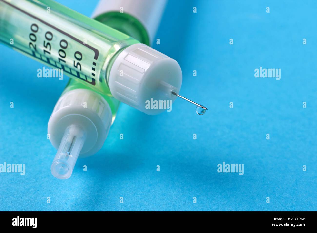 Mit Insulinspritzen werden Pens mit einem Tropfen Arzneimittel in Nahaufnahme auf der Nadel in einem Stapel auf blauem Hintergrund verpackt. Stockfoto