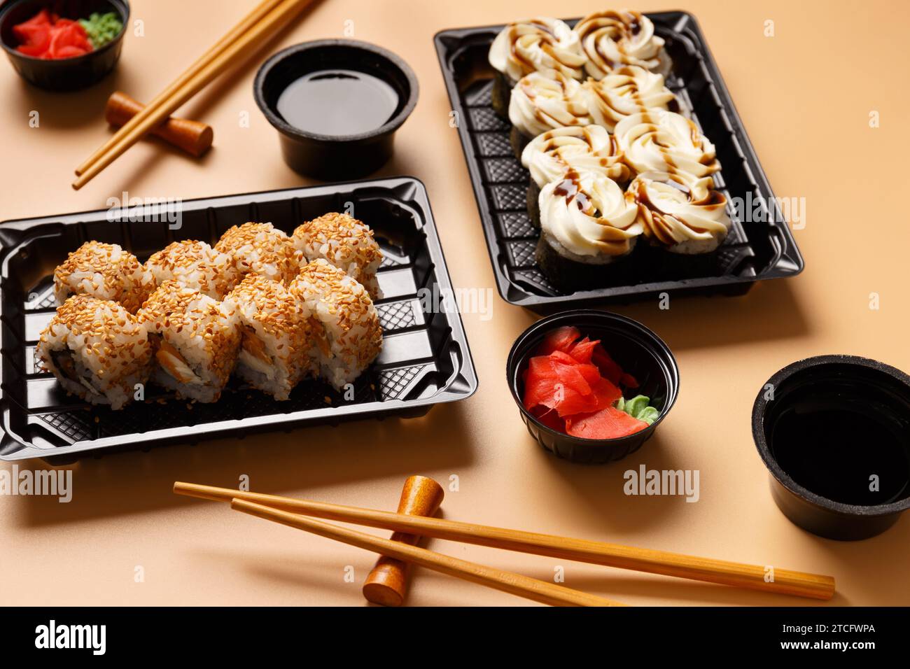 Set aus Sushi-Brötchen mit Lachs, Frischkäse, Sesamsamen in einer Plastikverpackung, chinesischen Sticks, Sojasauce auf hellem Hintergrund. Lieferung von Sushi Stockfoto
