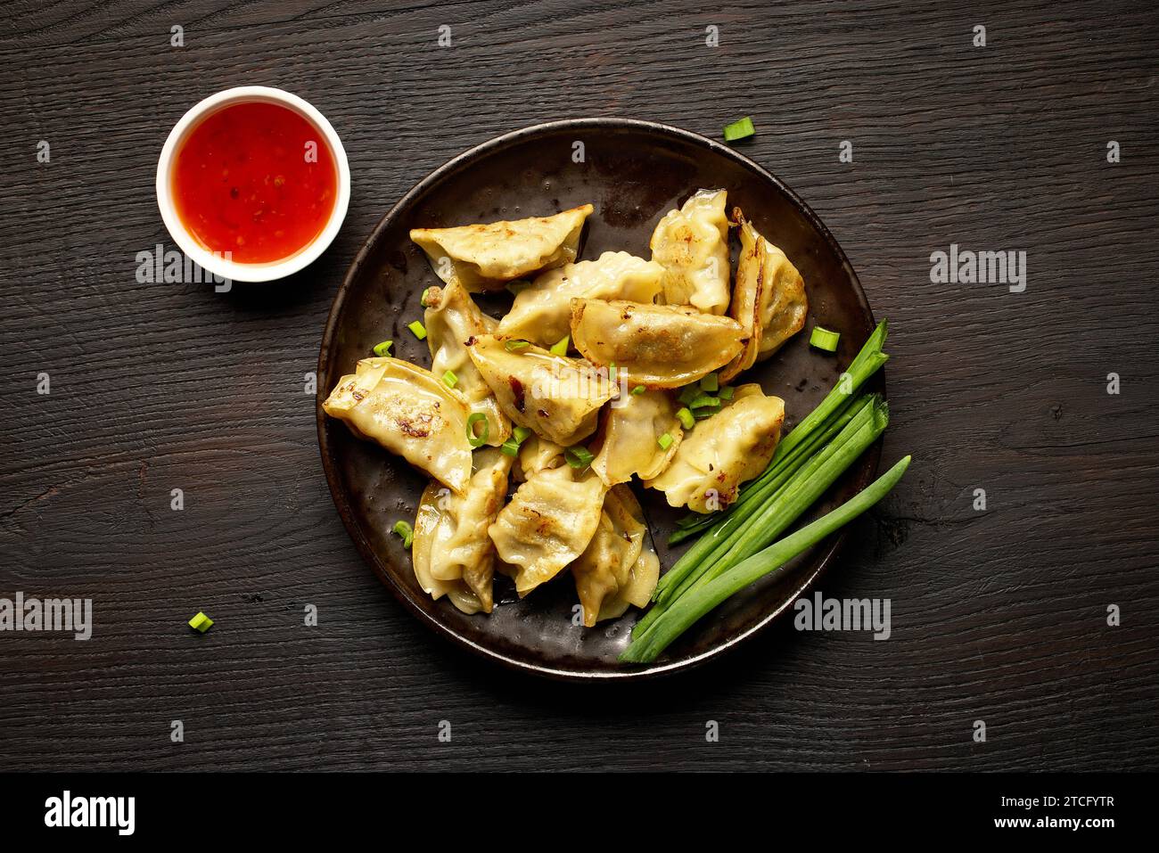 Teller mit asiatischen Knödeln auf dunklem Holztisch, Blick von oben Stockfoto