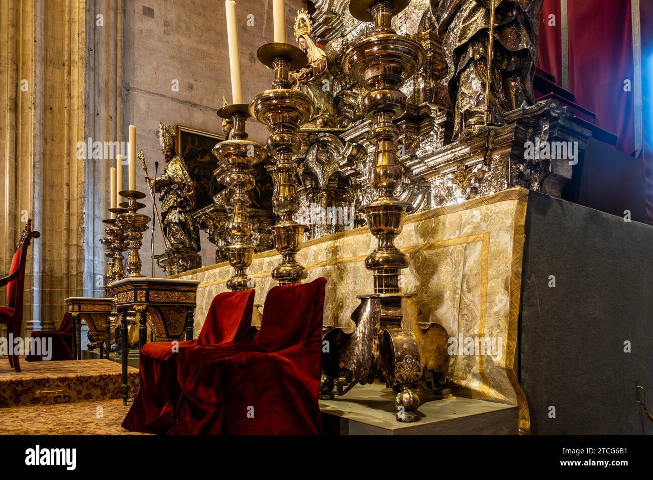 Großer Altar mit hoch aufragenden Kerzenleuchtern und verzierten Details in der Kathedrale von Sevilla, Spanien, die zum UNESCO-Weltkulturerbe gehört. Stockfoto