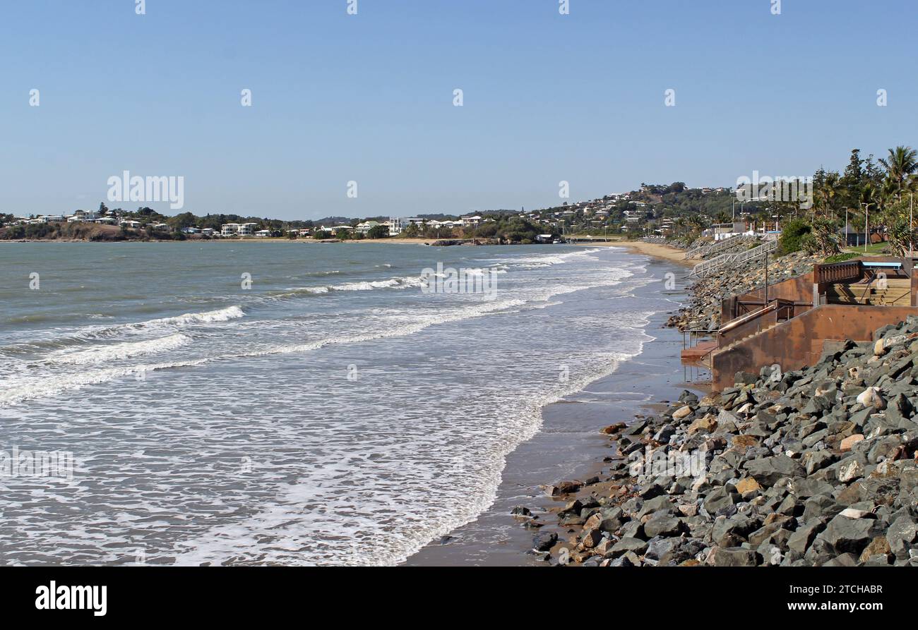 Blick auf den Strand, das Meer und die Felsen mit der Stadt Yeppoon im Hintergrund in Queensland, Australien Stockfoto