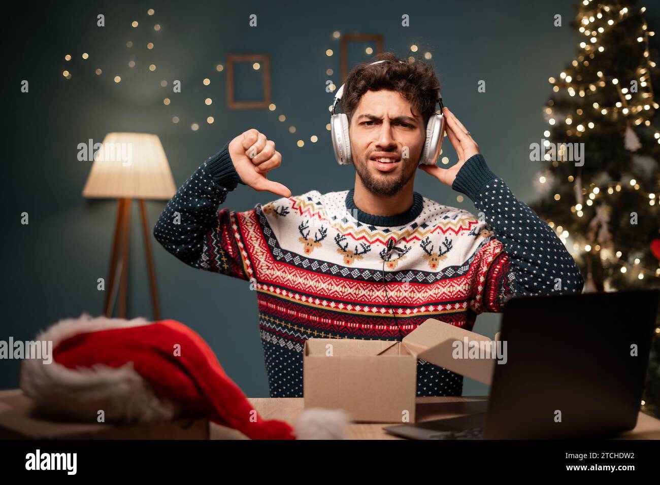 Video auspacken. Der aufgeregte arabische Mann mit Weihnachtsmütze zeigt seinen Anhängern neue Kopfhörer, während er am Heiligabend für soziale Netzwerke streamt Stockfoto