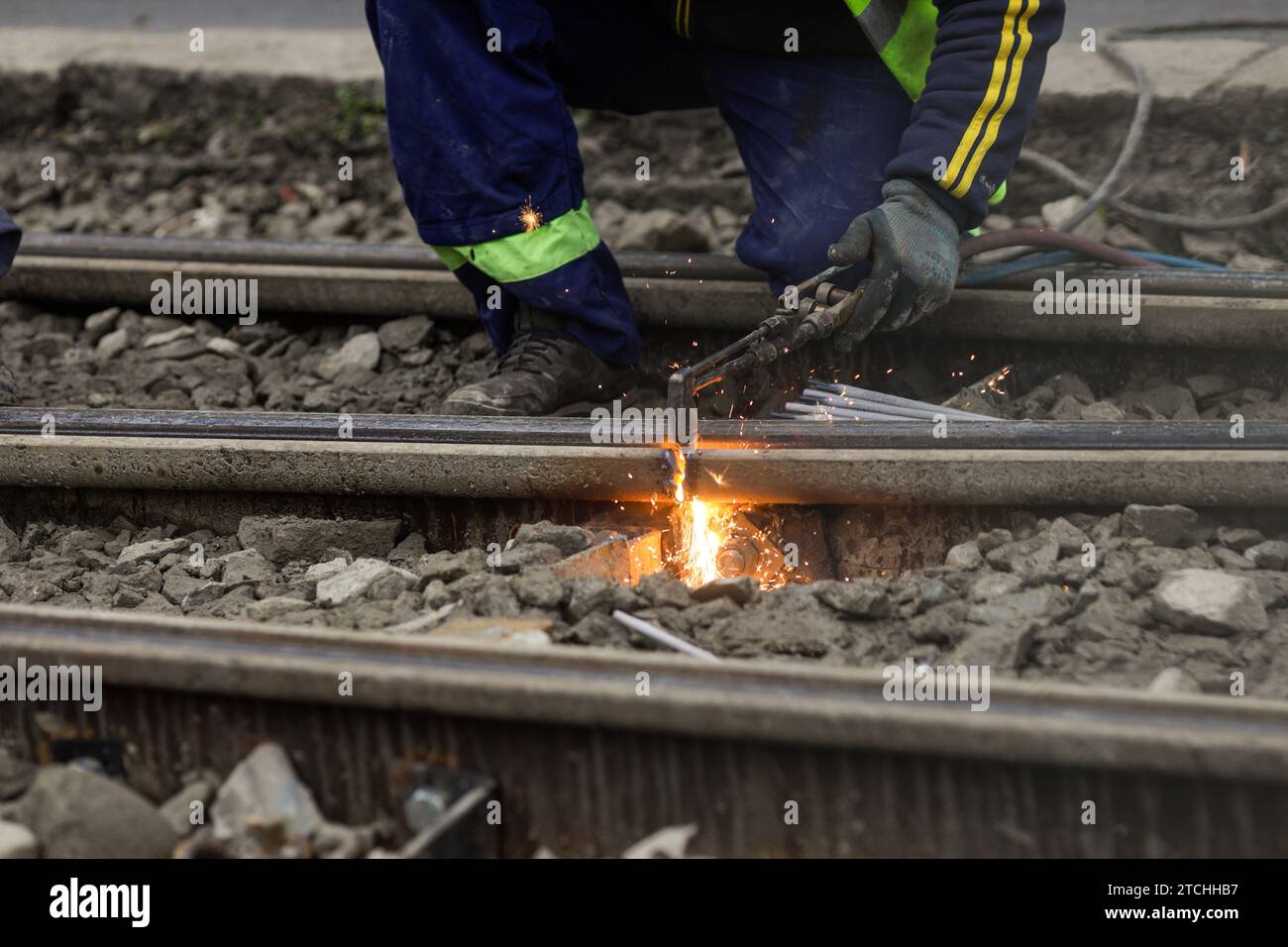 Details mit einem Arbeiter, der eine Oxy-Acetylen-Taschenlampe zum Schneiden von Straßenbahnschienen aus Metall verwendet. Stockfoto