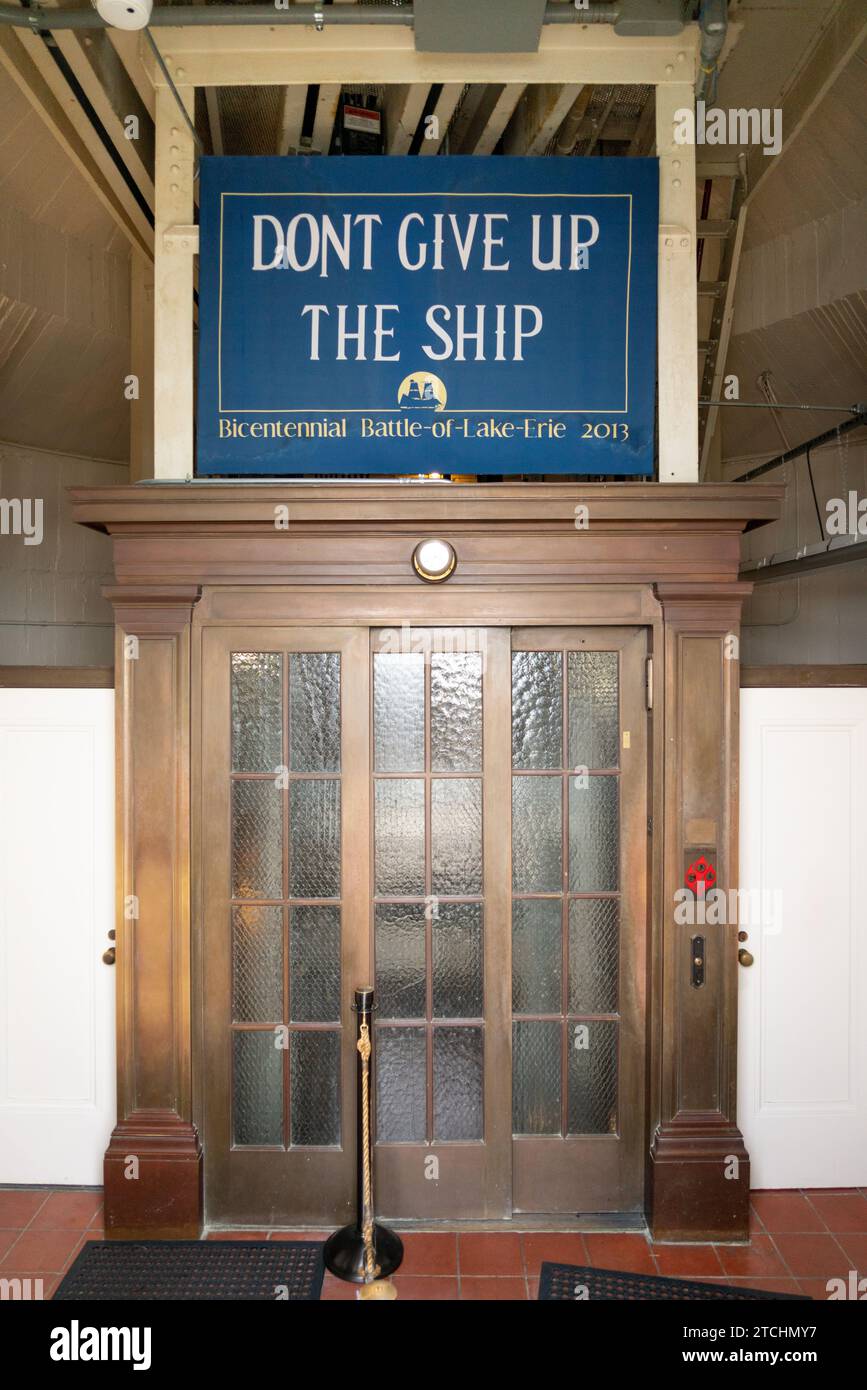 Das blaue Schild „Dont Give Up The Ship“ über hohen, messinggerahmten Türen mit Milchglasscheiben am Perry's Victory Memorial, Put-in-Bay, Ohio. Stockfoto