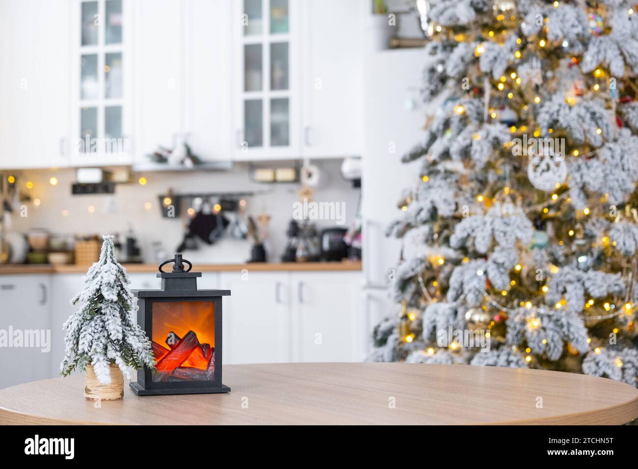 Festliche Weihnachtsdekoration auf einem runden leeren Tisch mit Platz für Text in weißer Küche, moderne Einrichtung mit einem Weihnachtsbaum und Feenlichtern. Neujahr, Stockfoto