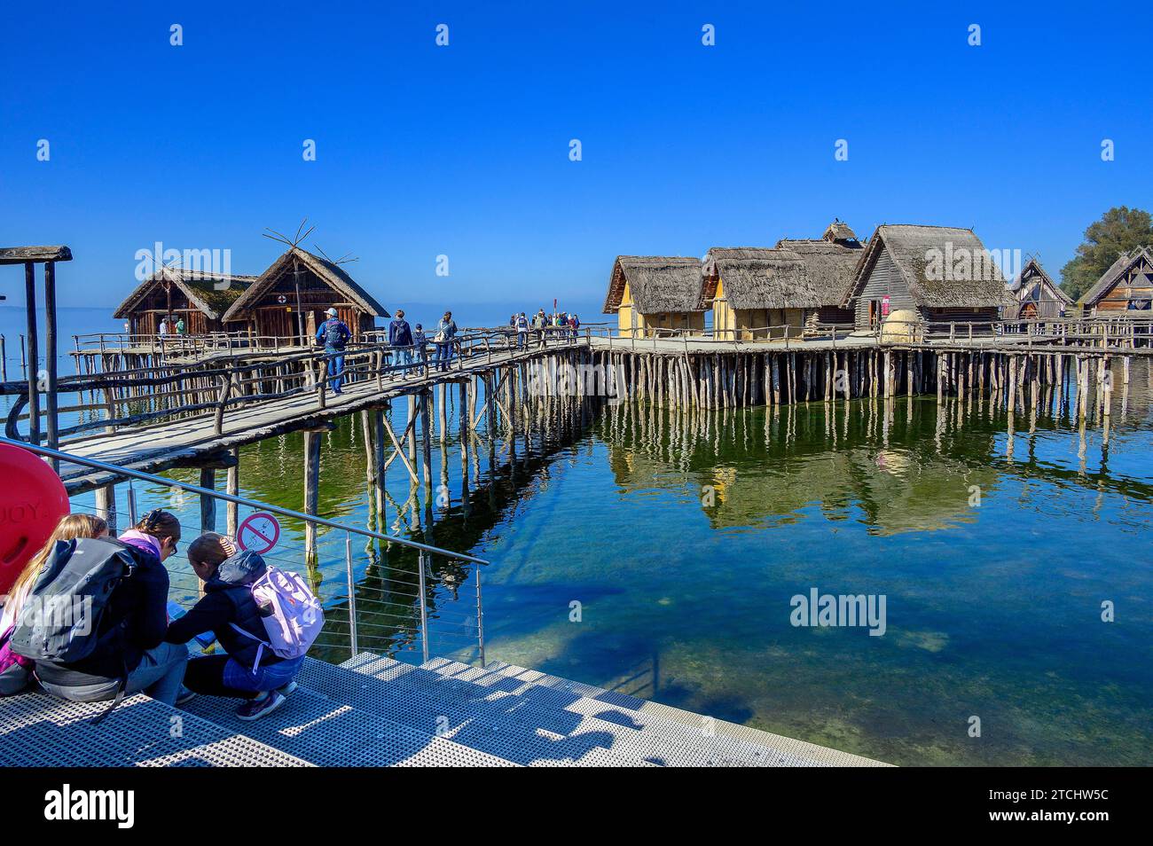 Touristen in den Pfahlbauten am Ufer des Bodensees, einer Touristenattraktion der Region und dem ältesten archäologischen Freilichtmuseum in Stockfoto