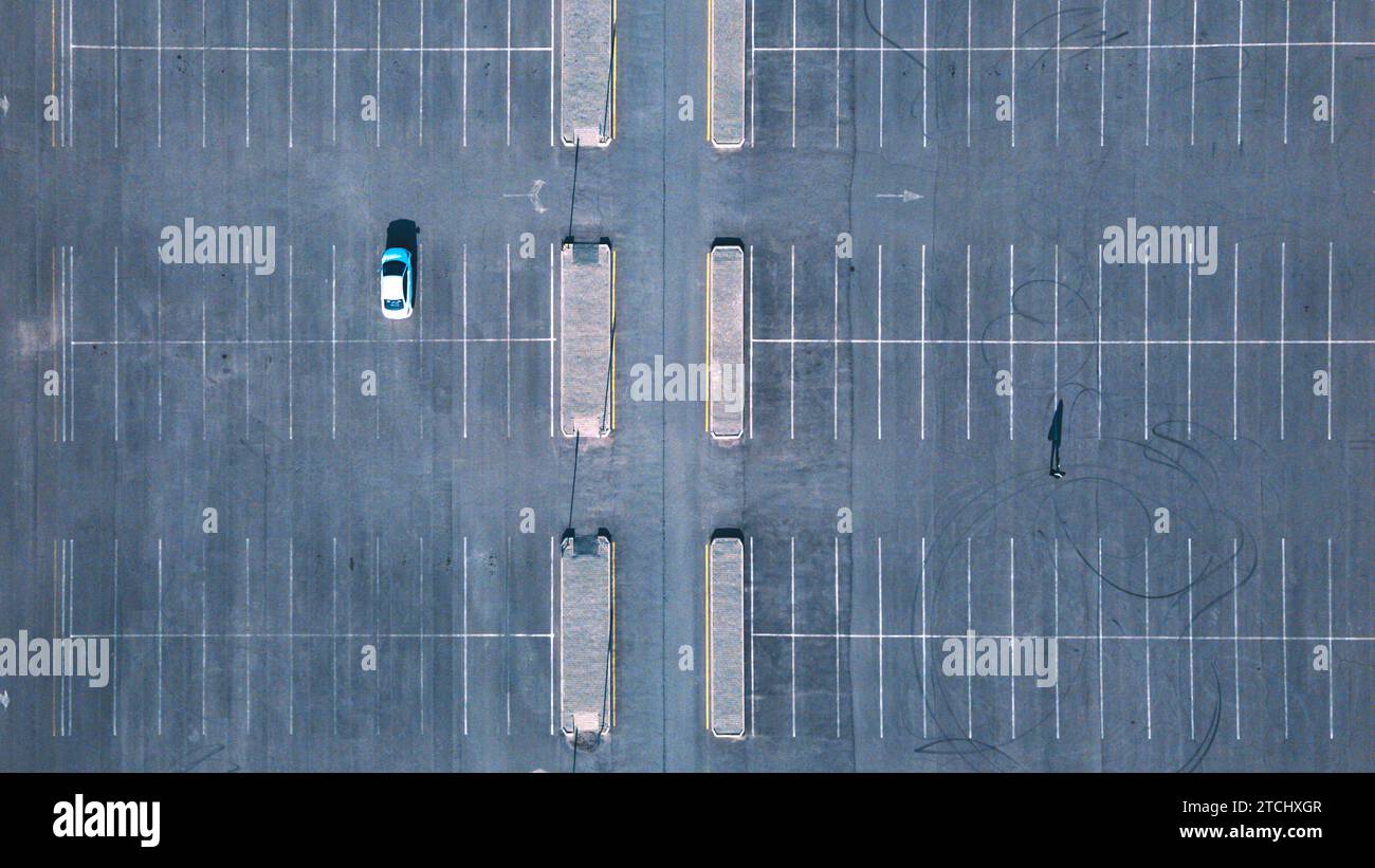 Großer Parkplatz mit einem Auto und einer Person. Blick von einer Drohne Stockfoto