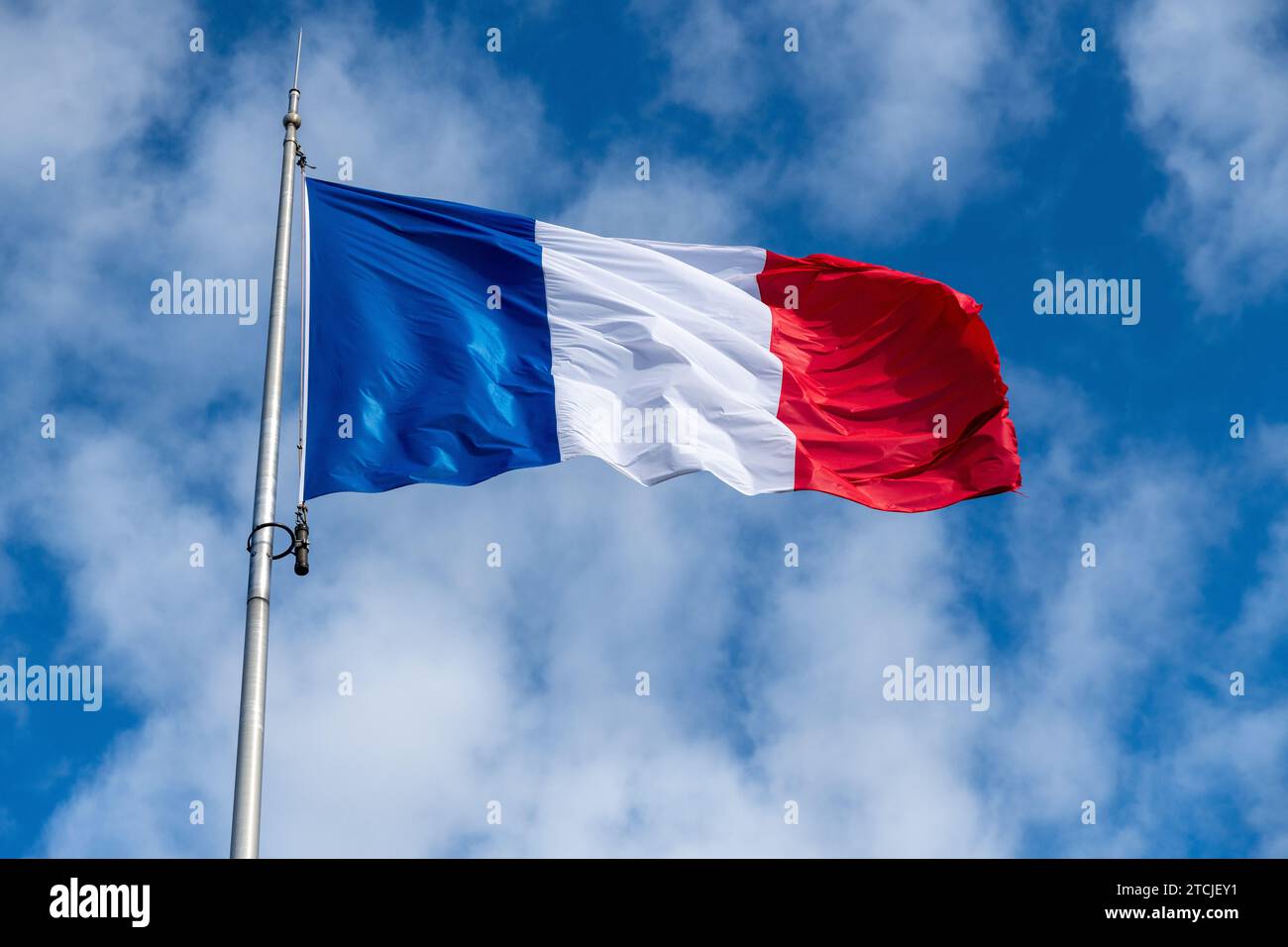 Die französische Flagge im Wind vor einem blauen Himmel mit Schleierwolken und einem wunderschönen Licht. Die Flagge hat die Farbe blau weiß und rot Stockfoto