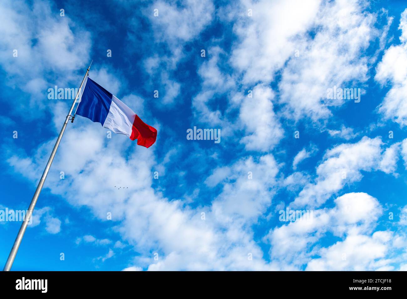 Die französische Flagge im Wind vor einem blauen Himmel mit Schleierwolken und einem wunderschönen Licht. Die Flagge wird rechtzeitig auf dem Foto mit viel von positioniert Stockfoto