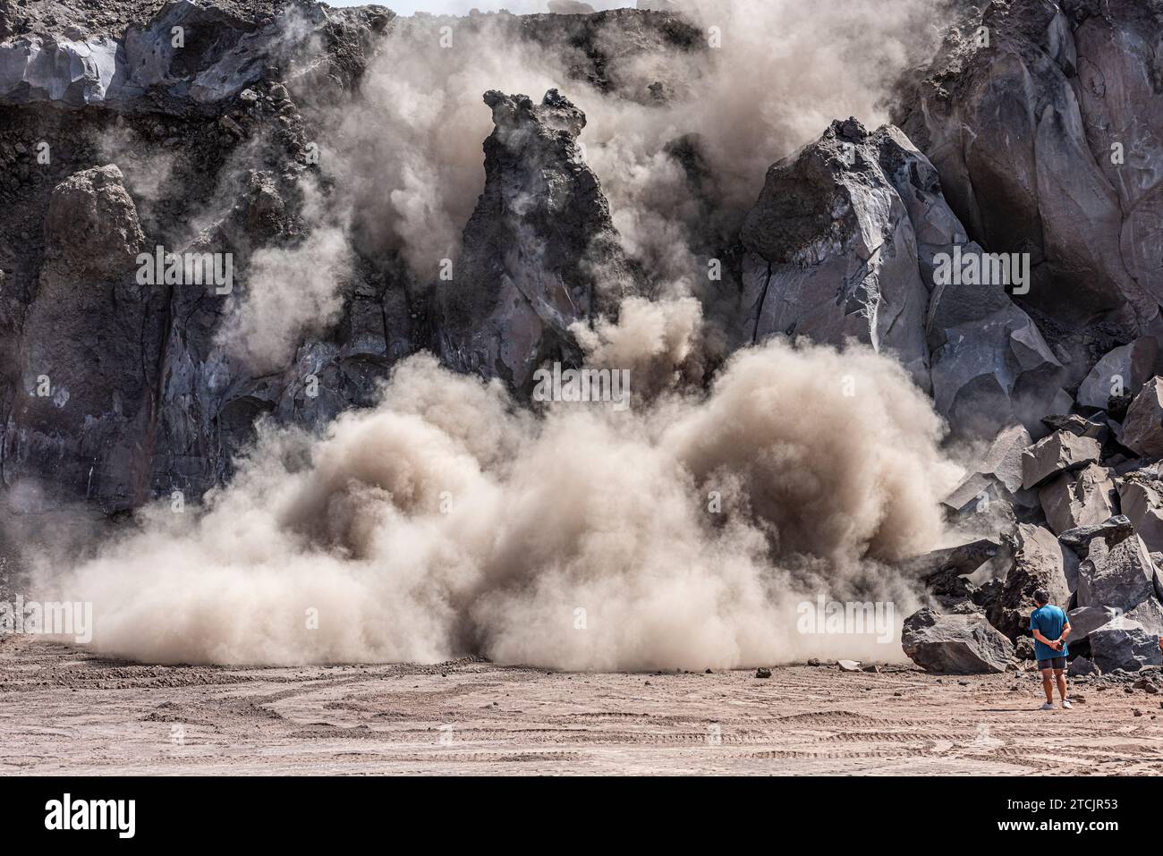 Gewinnung von vulkanischem Basaltgestein in einem Steinbruch an den Hängen des Ätna auf Sizilien. Eine riesige Platte wird mit einem Bagger von der Klippe dahinter abgetrennt Stockfoto