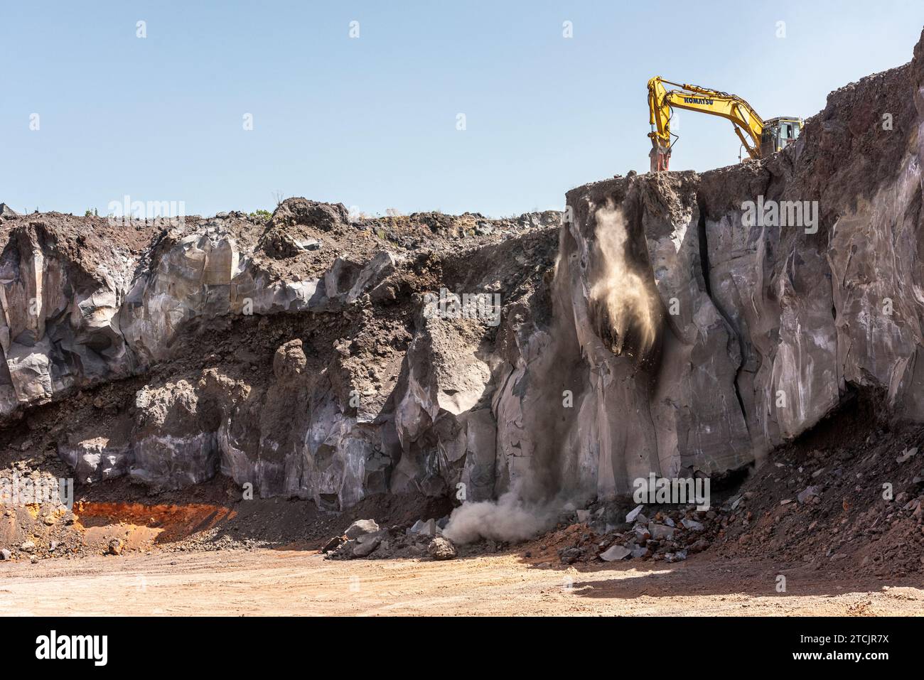 Gewinnung von vulkanischem Basaltgestein in einem Steinbruch an den Hängen des Ätna auf Sizilien. Ein am Bagger montierter Gesteinssplitter wird verwendet, um eine riesige Platte abzubauen Stockfoto