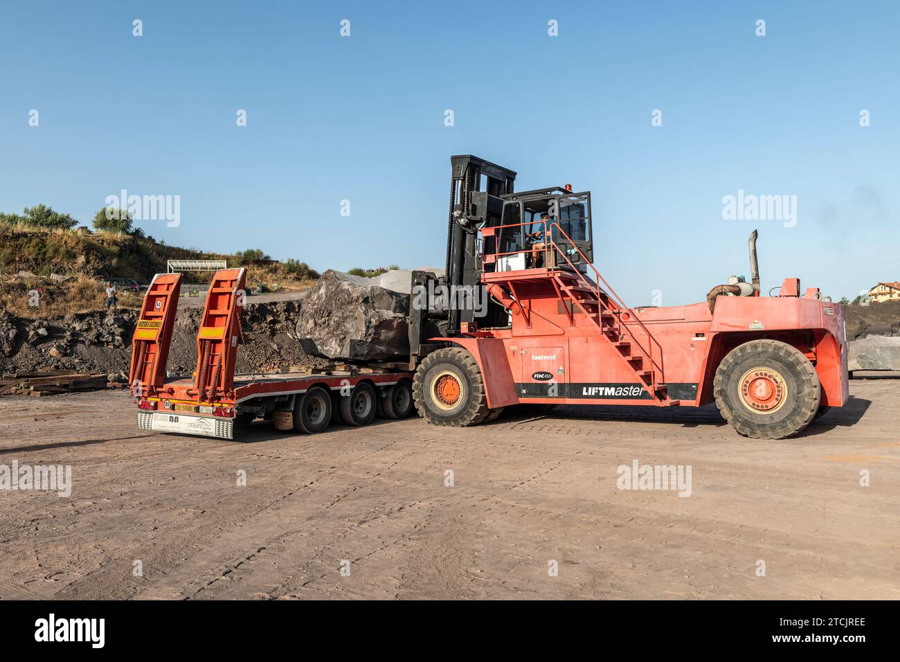 Gewinnung von vulkanischem Basaltgestein in einem Steinbruch an den Hängen des Ätna auf Sizilien. Riesige Platten werden vorsichtig geladen, bevor sie entfernt und zugeschnitten werden Stockfoto