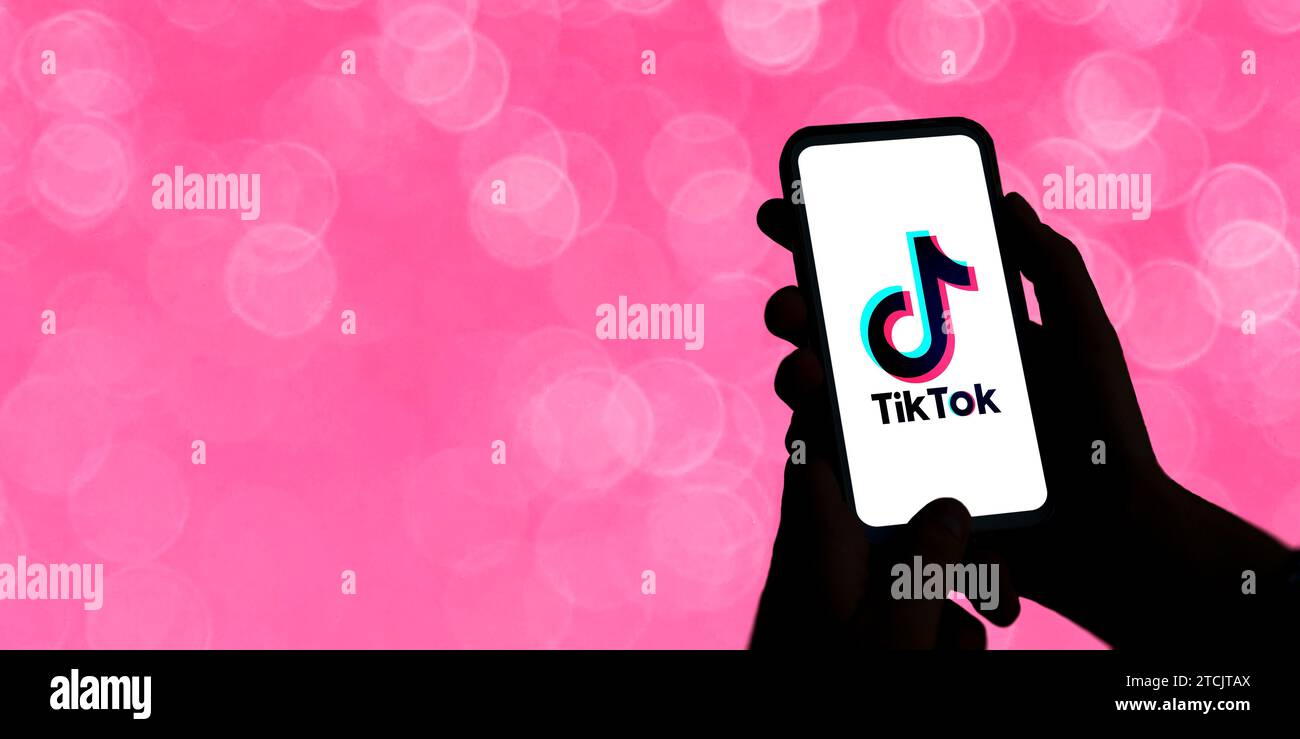 Frau, die ein Handy mit dem TikTok-Logo auf dem Bildschirm hält. Unterhaltung, kurzes Video, soziales Netzwerk. Illustration mit Teenager-Konzept. Hoher Kontrast Stockfoto