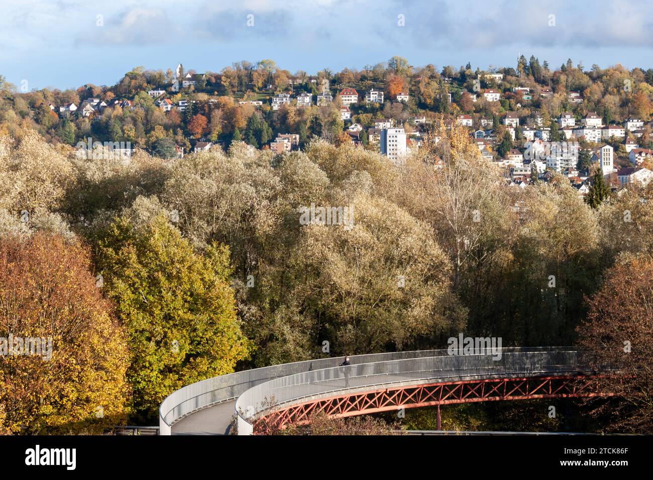 Fußgängerbrücke zwischen Herbstbäumen. Eine Stadt auf einem Hügel in der Ferne. Deutschland, Ravensburg Stockfoto