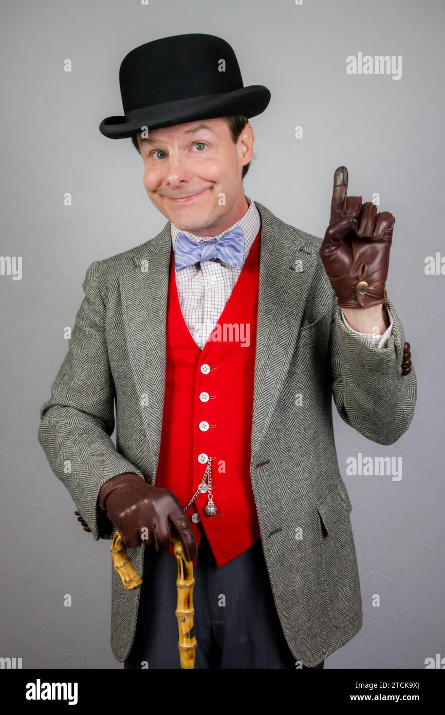 Porträt eines britischen Vintage-Gentleman in Tweedjacke und roter Weste mit Regenschirm. Vintage-Stil und Retro-Mode des klassischen Vaudeville pro Person Stockfoto