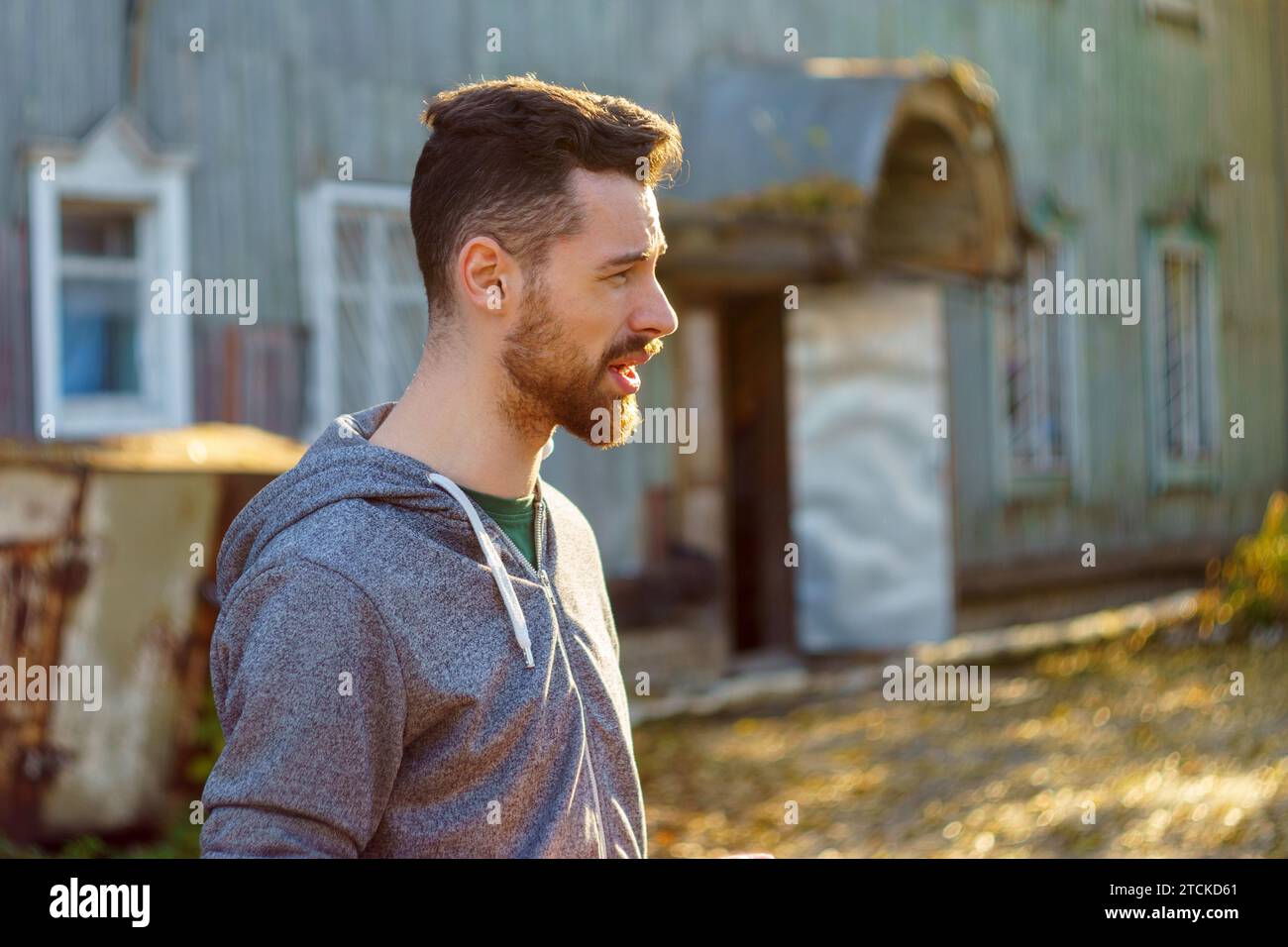 Brutaler, gutaussehender Mann, 30-35 Jahre alt, steht im Park in einem grauen Sweatshirt Stockfoto
