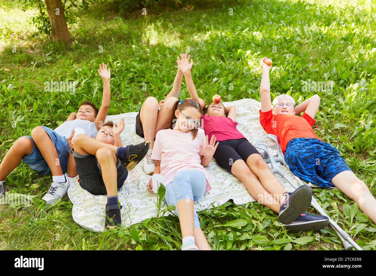 Gruppe glücklicher Kinder, einschließlich behinderter Junge beim Picknick in der Natur Stockfoto