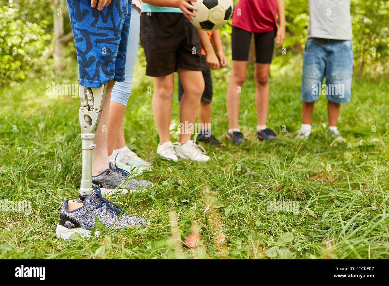 Niedriger Teil eines behinderten Jungen mit amputiertem Bein, der mit Freunden im Park steht Stockfoto