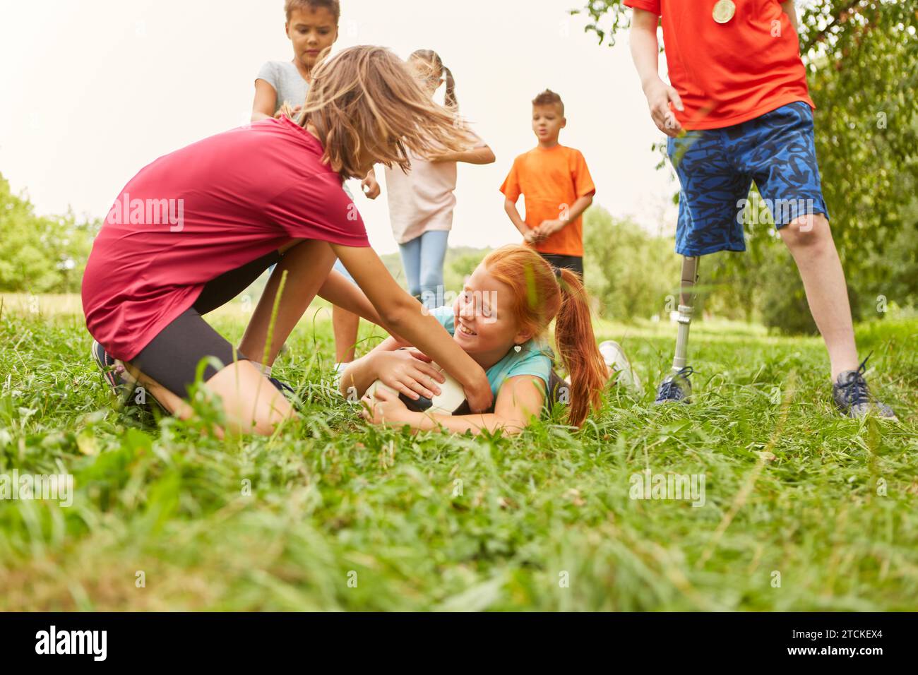 Freundinnen, die Spaß haben, während sie Fußball auf dem Gras im Park spielen Stockfoto