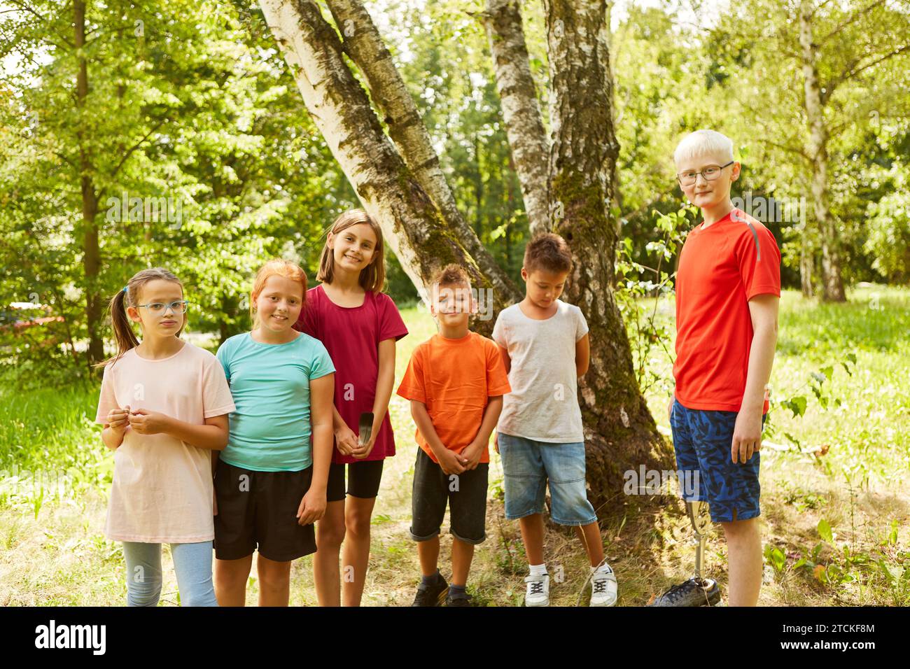 Gruppe glücklicher Kinder mit behindertem Jungen in der Natur als Inklusionskonzept Stockfoto