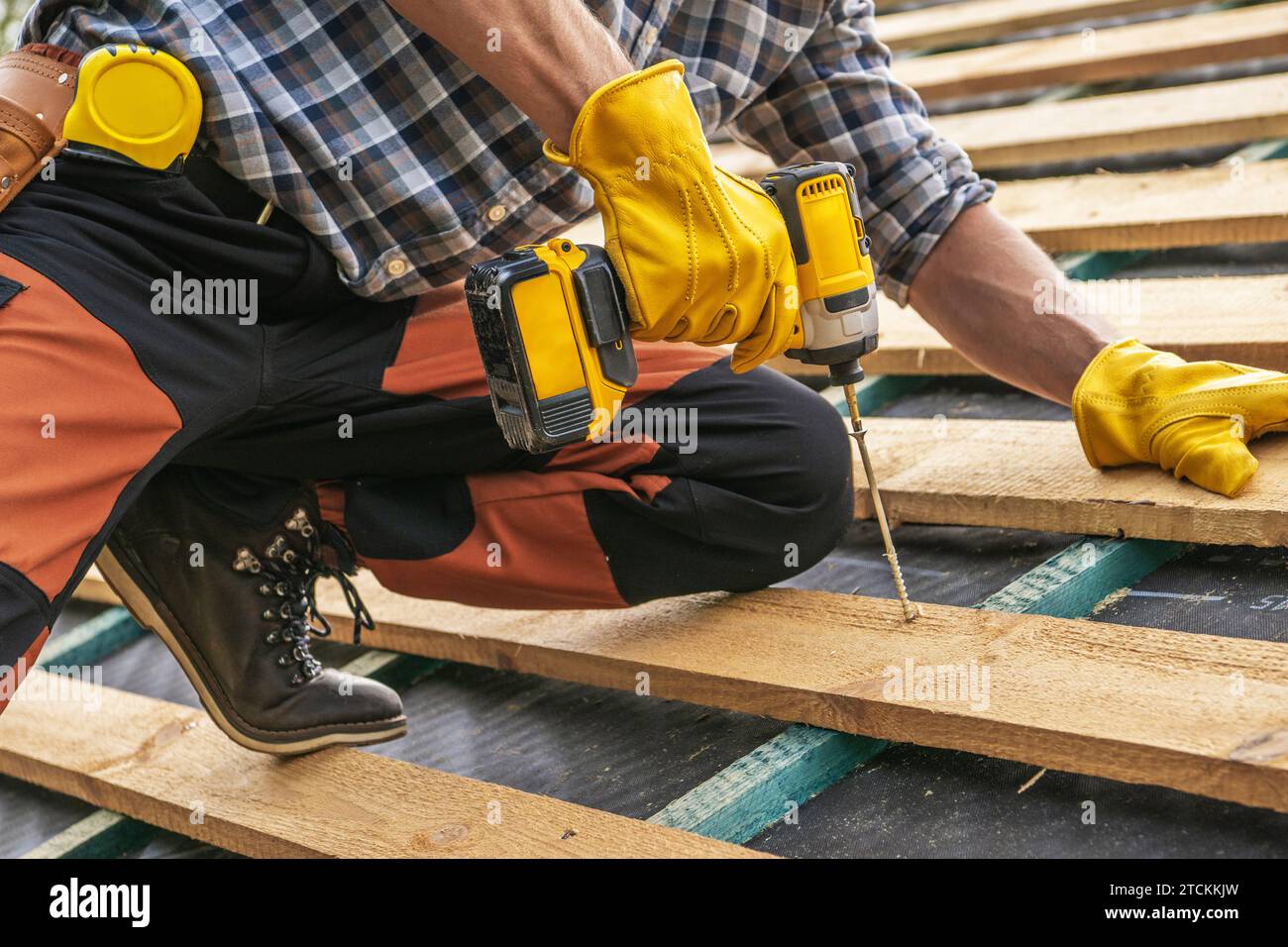 Baustellenunternehmer mit Bohrschrauber, Montage von Dielen für die Enddachabdeckung in Nahaufnahme Stockfoto