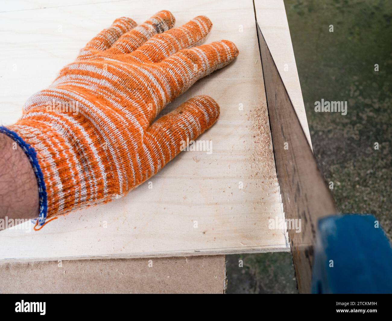 POV-Ansicht des Zimmermanns, der Sperrholz mit Bügelsäge im Freien sägt Stockfoto