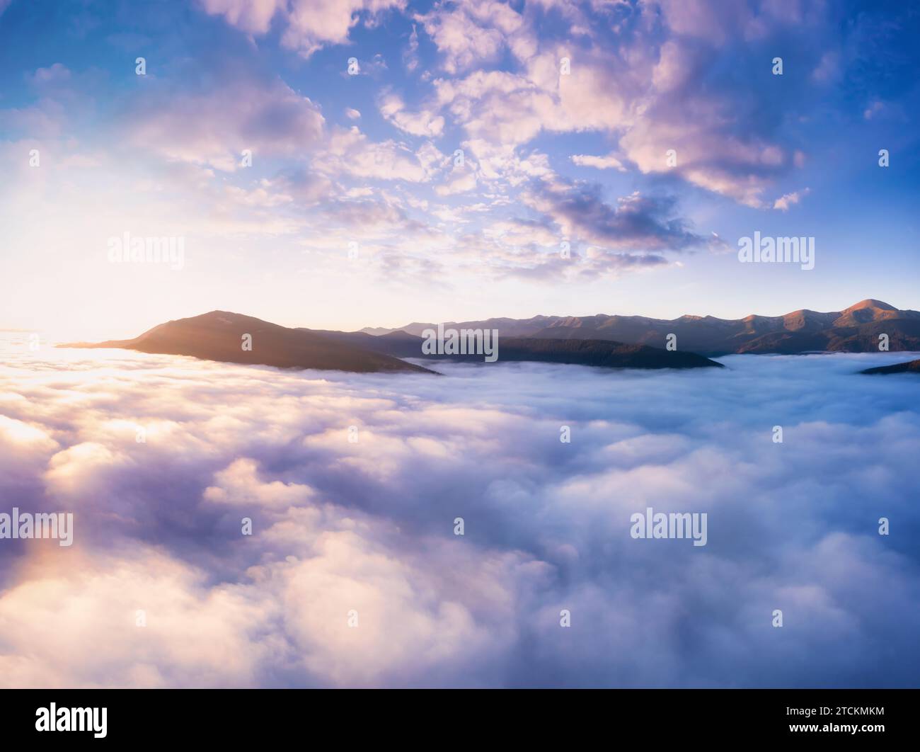 Berge in niedrigem dichtem Nebel am Morgen Sonnenaufgang. Wunderschöne Landschaft mit Berggipfeln im Nebel. Bergtal in Wolken. Stockfoto